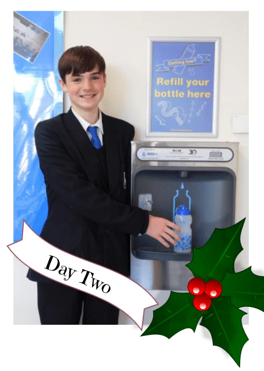 One of the pupils posing with our bottle refill station installed in their school.