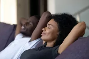 Couple sitting on a sofa relaxing with their hands behind their heads